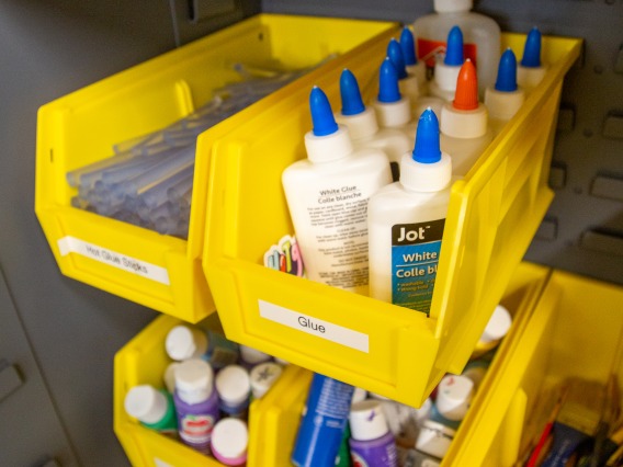 Several yellow bins containing crafting items such as glue and markers