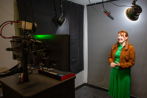 A library staff member records a video presentation in the One Button Studio in front of the green screen.